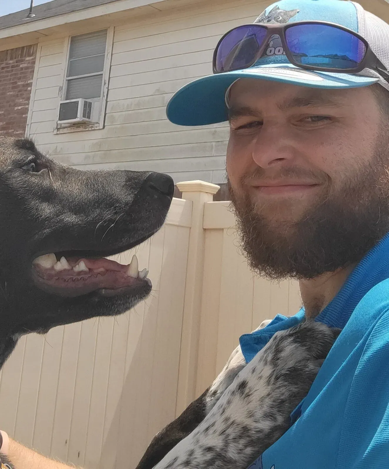 Brandon with a customer's black dog beside a white fence